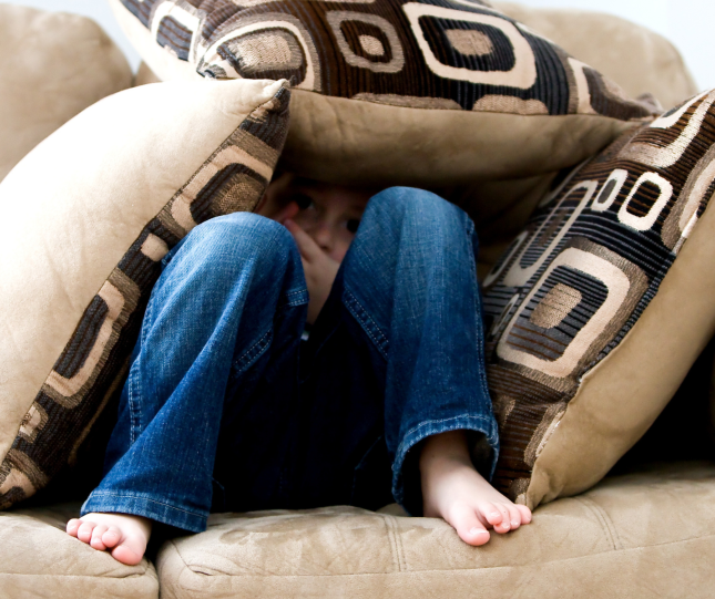 Child hiding in cushions on couch 