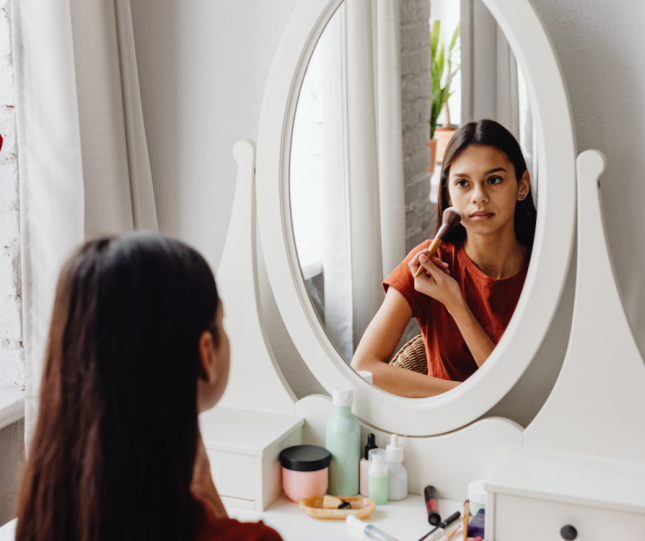 Teen putting on makeup in mirror