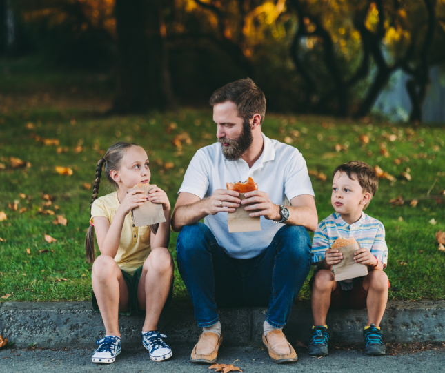 Father eating hamburgers with children held in wrappers
