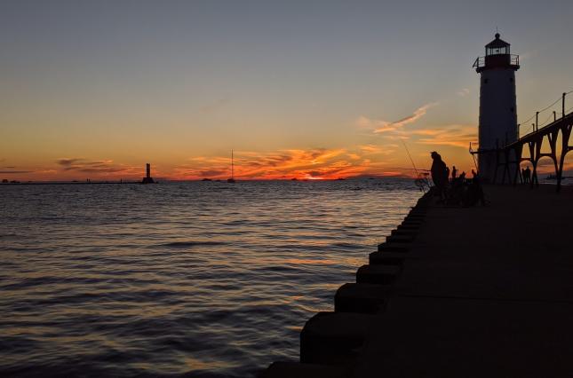 Picture of Lake Michigan at sunset with silhouetted dock and lighthouse. Credit Jennifer Schlicht