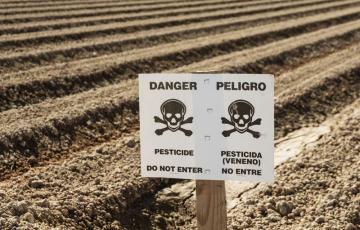 Farm field with a pesticide warning sign. Photo credit: Tom Grundy / Shutterstock